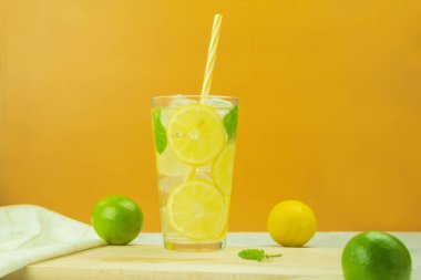 Taze limondan soğuk limonata ve sarı arka planda nane şekeri. Limonlu limonata ve arkaplanda nane şekeri. Boşluğu kopyala