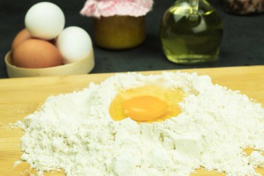 Unlu taze ve çiğ tavuk yumurtası. Parlak yumurta sarısı ve buğday unu rengi. Masada pişirmek için gerekli malzemeler. Metin için kopyalama alanı olan arkaplan