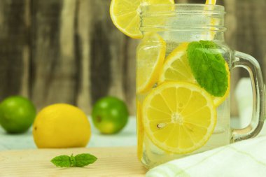 Köy arka planında naneli taze limonata. Limonata ve ahşap arka plandaki malzemeler, kopyalama alanı. Limonlu yaz limonatası ve sarı, güneşli bir arka planda nane.