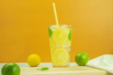 Taze ve soğuk limonlu bir bardak. Sarı arka planda limonata. Limonlu ve naneli mojito kokteyli. Metin için yer