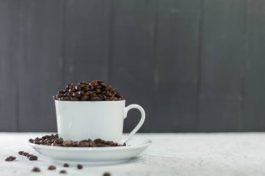 Beyaz fincan ve kokulu kahve çekirdekleri. Kahve fincanı, tarçınlı, kahve çekirdekli. Boşluğu kopyala