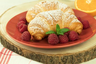 Kruvasan ve taze ahududu, taze ve lezzetli kruvasanlar. Otelde kahvaltı: sütlü kahve ve kruvasan, ahududu ve ahşap masa. Kopyalama alanı olan arkaplan