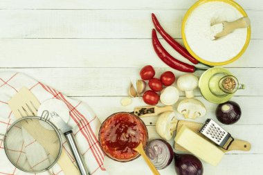 Pizza yapmak için gerekli malzemeler masada. Pizza pişirme süreci: hamur, merdane, yumurta, tereyağı ve buğday unu ahşap bir masada. Metin için alanı olan arkaplan