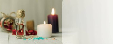 Aroma yağı şişesi ve aroma mumları. Arka planda mesaj için yer var. Yakın plan, şişedeki yağ ve arka plandaki spa mumları. Spa, arka planda mumlar.
