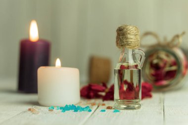 Aroma yağı şişesi ve aroma mumları. Arka planda mesaj için yer var. Yakın plan, şişedeki yağ ve arka plandaki spa mumları. Spa, arka planda mumlar.