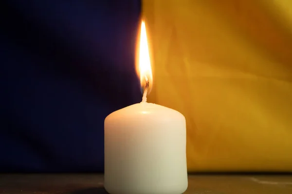 ウクライナの国旗を背景に1本のロウソクを燃やす コピースペースの背景 追悼のろうそく 記憶と悲しみ — ストック写真