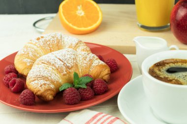 Ahşap bir arka planda taze kruvasan ve kahve. Kahvaltı, bir fincan kahve ve taze kruvasan, meyveli.