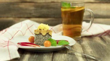 Delicious sponge cake with poppy filling. A piece of cake on a white plate and decorated with fruits and sauces. Physilis berries. Background with copy space. Camera zoom