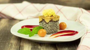 Delicious sponge cake with poppy filling. A piece of cake on a white plate and decorated with fruits and sauces. Physilis berries. Background with copy space. Camera zoom