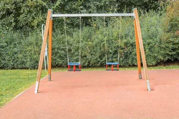 Modern children\'s swing on the playground in the park. Hanging swings on the playground. The playground has an artificial soft surface.