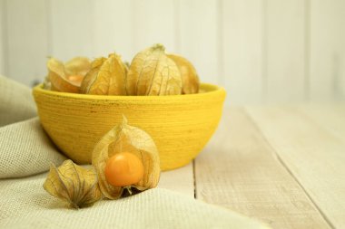 Small yellow physalis berries on a wooden background. Physalis fruits on a wooden table. Sweet yellow physalis berries. Copy space