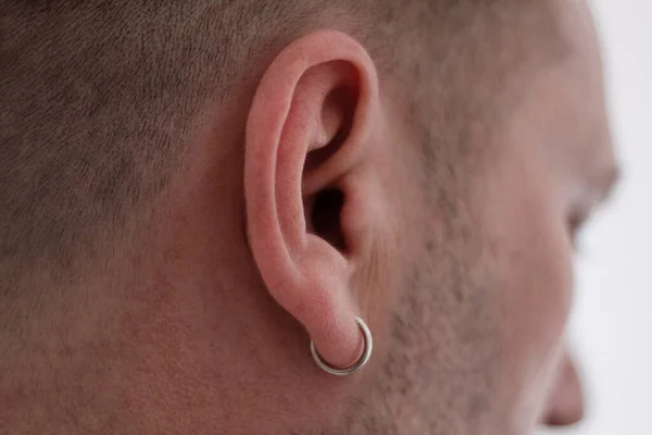 Earring in the ear, Close-up, Piercing in the ear Men. Silver earring. Silver men's jewelry