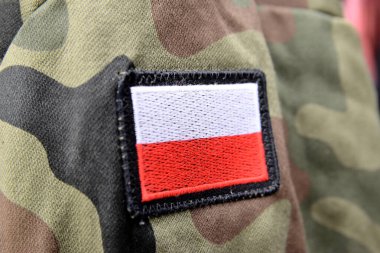 Close-up of a camo military uniform with the emblem of the Polish flag. 