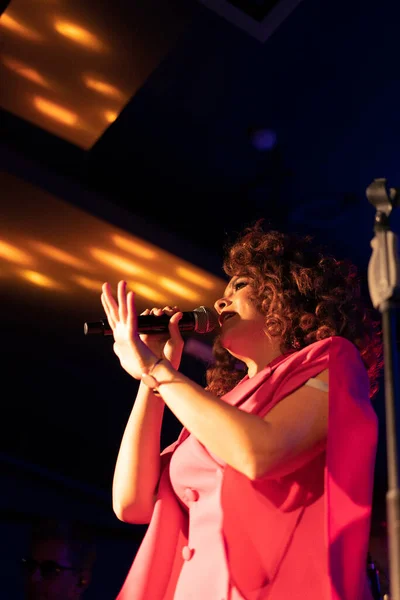 美しい明るいカリスマ女性歌手がコンサートにステージ上で歌います — ストック写真