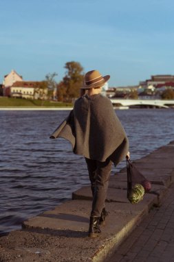 Büyük bir şehrin ortasında kısa saçlı, şapkalı, orta yaşlı güzel bir kadın. Yakın plan portre, yumuşak arka plan ışığı.