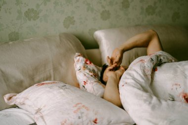 Adam yatakta, sabah, uyanıyor, yatakta tembellik ediyor.