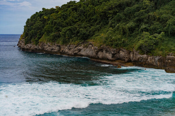 тропический фон, пляж с голубой водой, волны разбиваются на камне