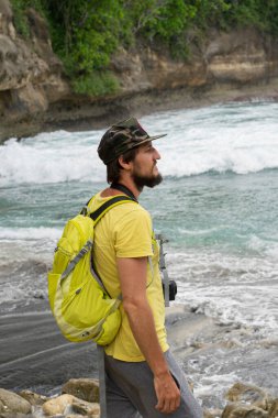 Sırt çantası ve fotoğraf makinesi olan şapkalı genç bir gezgin...