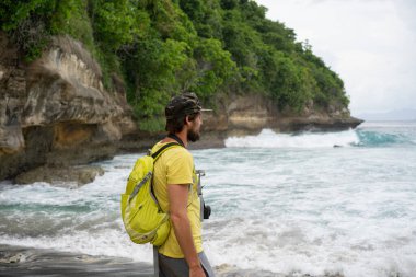 Sırt çantası ve fotoğraf makinesi olan şapkalı genç bir gezgin...
