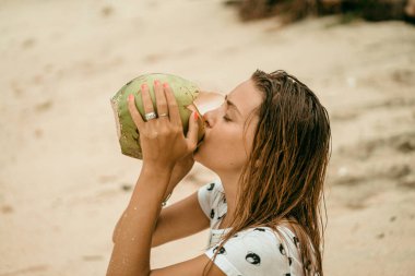 Genç ve güzel bir kadın hindistan cevizi suyu içiyor.