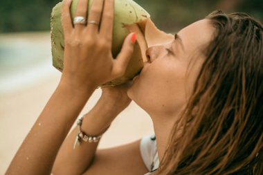 Genç ve güzel bir kadın hindistan cevizi suyu içiyor.