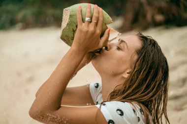 Genç ve güzel bir kadın hindistan cevizi suyu içiyor.