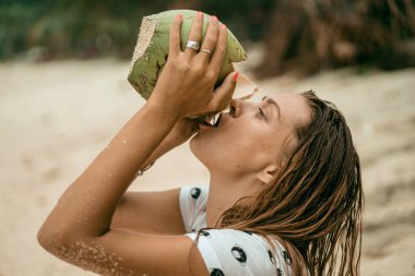 Genç ve güzel bir kadın hindistan cevizi suyu içiyor.