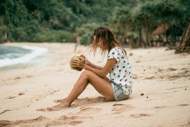 Genç ve güzel bir kadın hindistan cevizi suyu içiyor.