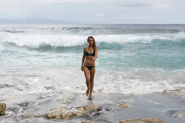 海の近くのビーチで水着で長いブロンドの髪を持つ美しい若い細い女性 ビーチでリラックスしてください 熱帯の休暇だ 女が泳いで水の中に入る — ストック写真