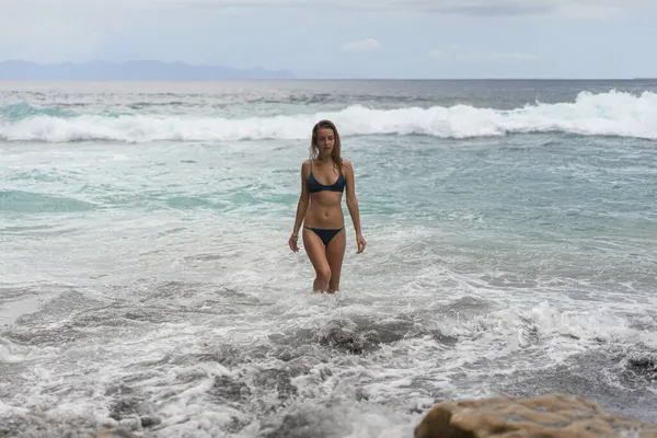 海の近くのビーチで水着で長いブロンドの髪を持つ美しい若い細い女性 ビーチでリラックスしてください 熱帯の休暇だ 女が泳いで水の中に入る — ストック写真