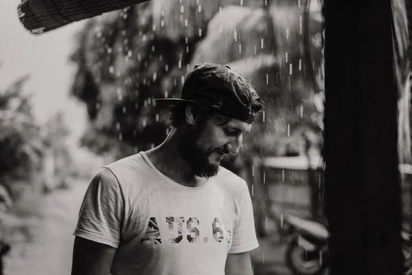 Tropikal Yağmurun Altında Şapkalı Yakışıklı Genç Sakallı Adam — Stok fotoğraf