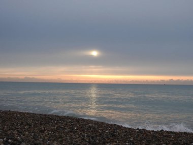 Denizin üzerinde gün doğarken, küçük bir yelkenli görünür.