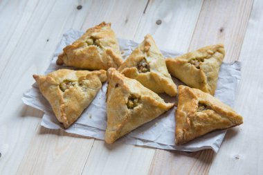 Traditional Tatar food triangle echpochmak samsa pie with meat and potato on baking paper, selective focus