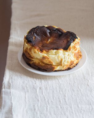 Beyaz arka planda beyaz bir tabakta San Sebastian Cheesecake 'in tamamı yanmış, seçici odaklı.