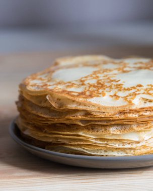 Ahşap arka planda gri tabakta Rus ince krepleri blini yığını. Yakın çekim, seçici odaklanma