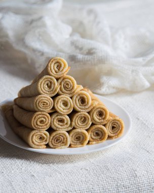 Kırsal arka planda beyaz tabakta Rus usulü rulo krep blini yığını. Yakın çekim, seçici odaklanma