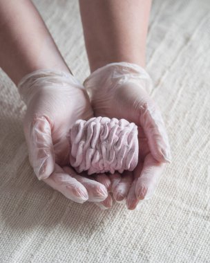 Bir kadının eldivenli eli taze ev yapımı marshmallow, lihgt arka plan, seçici odaklanma tutar.