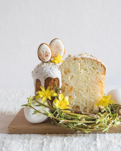 Paskalya kurabiyeleriyle süslenmiş geleneksel paskalya pastası, yuva şeklinde söğüt dalları, sarı çiçekler, keten masa örtüsünün üzerinde beyaz yumurtalar. Yan görüş, seçici odaklanma. Paskalya ziyafeti, tatil sembolü