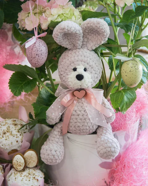 Paskalya süsleri. Paskalya usulü el yapımı oyuncak örgü tavşan, renkli yumurta, Paskalya pastası ve masada çiçekler..