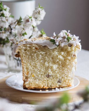 Geleneksel paskalya pastası ya da tatlı ekmek, elmalı brahces beyaz tabakta açık keten masa örtüsünde çiçek açıyor. Yan görüş, seçici odaklanma. Paskalya ziyafeti, tatil sembolü