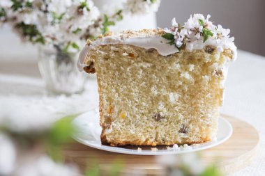 Geleneksel paskalya pastası ya da tatlı ekmek, elmalı brahces beyaz tabakta açık keten masa örtüsünde çiçek açıyor. Yan görüş, seçici odaklanma. Paskalya ziyafeti, tatil sembolü