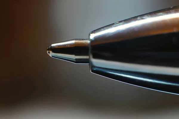 Extreme close up of a ballpoint pen tip with soft focus background