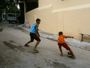Two boys playing soccer or football in the street in the village. San Mateo near metro Manila. Ph. 