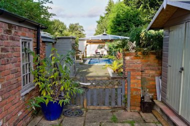 Güneşli bir günde, üzerinde tropikal bitkiler ve bir çardak olan bir bahçe.