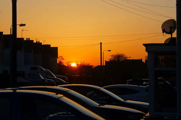 Stunning orange sky sunset with cars parked in foreground