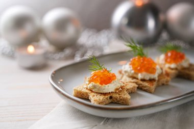 Kırmızı havyar, krema ve dereotlu kanepeler yıldız şeklinde kızarmış ekmek üzerinde gri bir tabakta, bayram gümüşü Noel süslemesi, kopya alanı, seçilmiş odak, dar alan derinliği