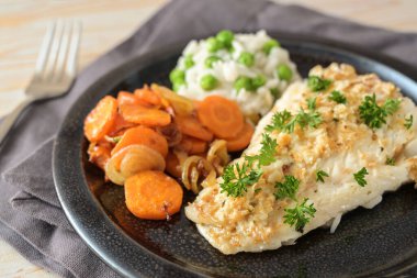 Baharatlı balık fileto ve maydanozlu garnitür, koyu tabakta yeşil bezelye pilavı, sağlıklı balık yemeği, yukarıdan yüksek açı, seçilmiş odak, çok dar alan derinliği.