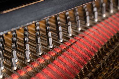 Akustik müzik enstrümanının bir parçası, seçilmiş odak noktası, dar bir alan derinliği olan eski bir piyanonun içinde bulunan ipli ve kırmızı raptiyeli raptiyelere ya da raptiyelere yakından bak.