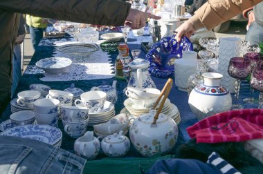 Güneşli bir günde kullanılmış sofra takımı ve kostüm ellerinin olduğu garaj satışı veya bit pazarı tezgahı, seçili odak, dar alan derinliği
