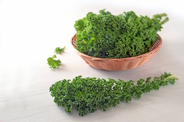 Kale ya da yeşil yaprak lahanası, bir kıvırcık yaprak ve daha fazlası beyaz bir sepetin içinde, vitamin açısından zengin kış sebzeleri, kopya alanı, seçilmiş odak, dar alan